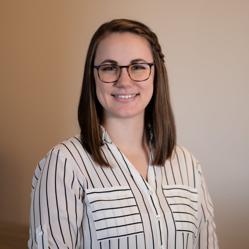 Dr. Addison Dempsey, audiologist, smiling in glasses and a white blouse with black stripes